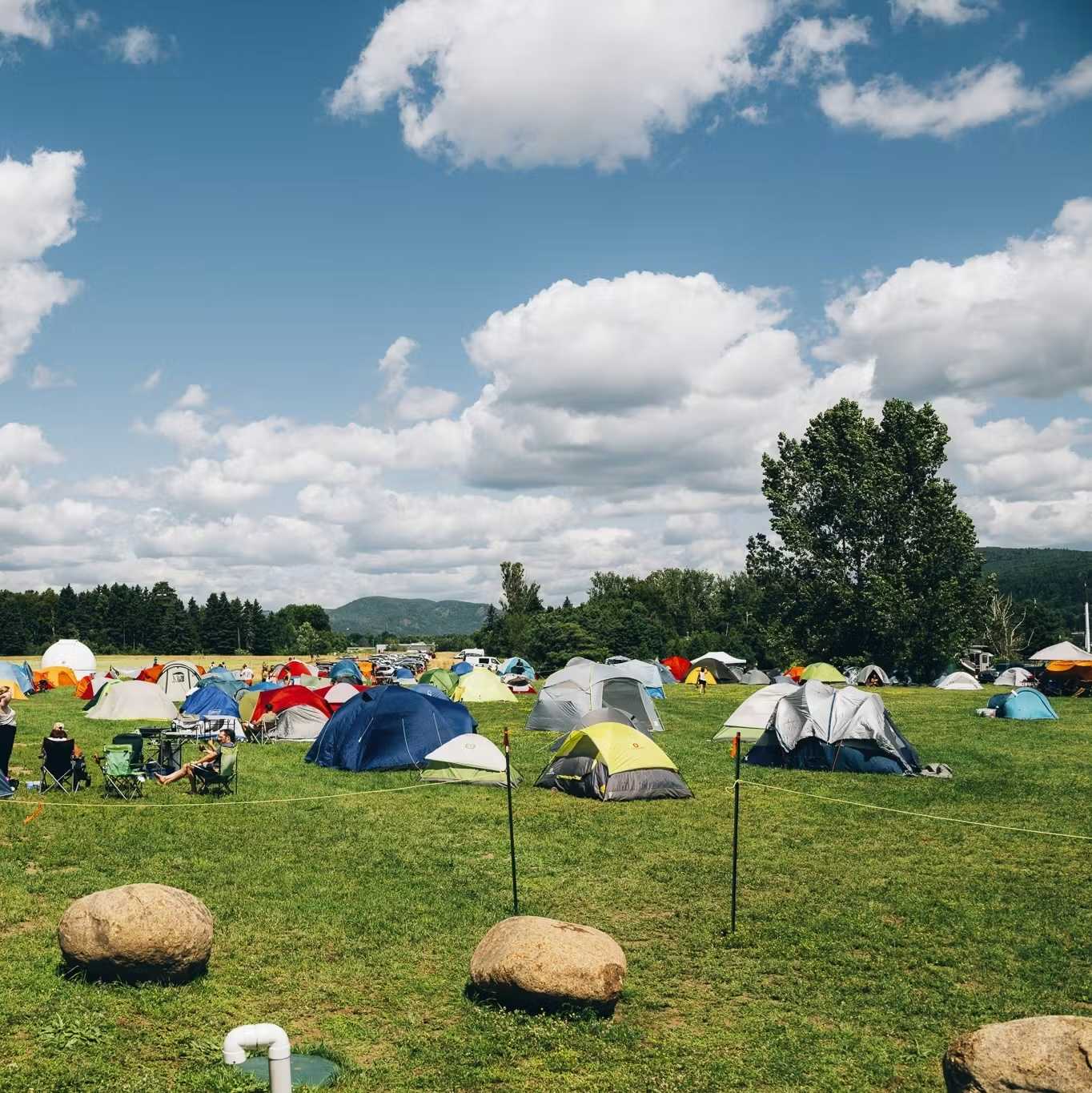 Tentes colorées installées dans un champ près d'un boisé